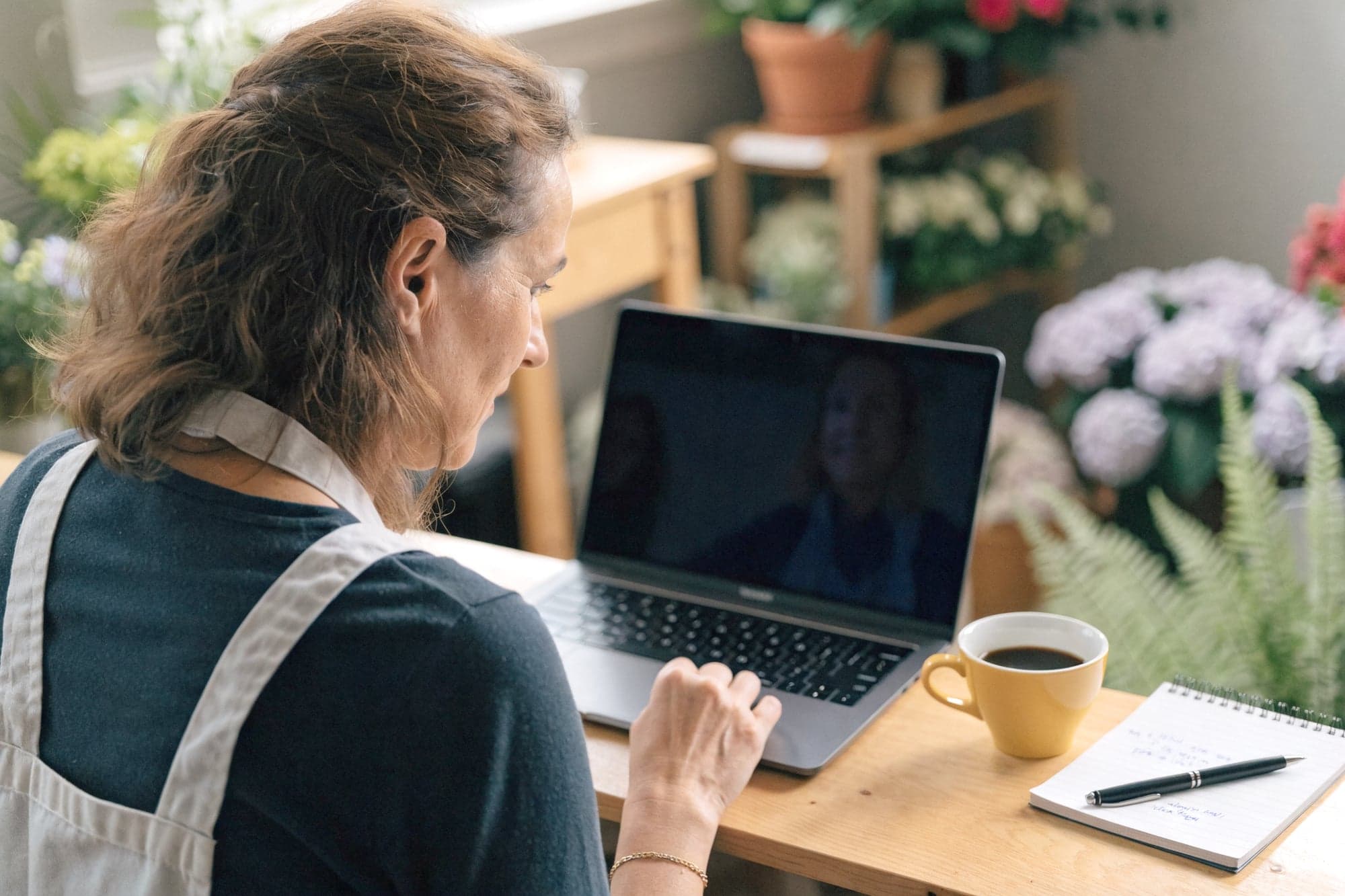 Inhaberin eines Blumenladens im Video-Erstgespräch am Laptop in ihrem Laden