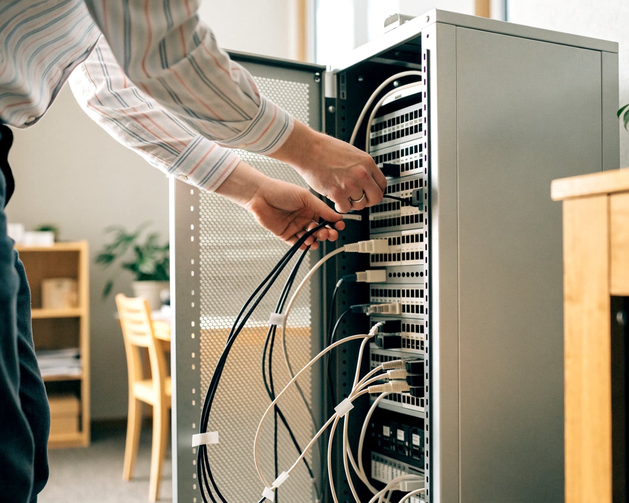 IT-Dienstleister verkabelt einen Netzwerkschrank beim Kunden