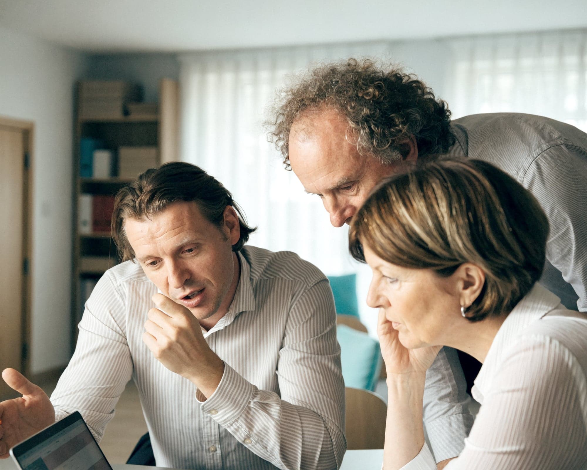 Berater bespricht mit zwei Geschäftsführern Unterlagen am Laptop