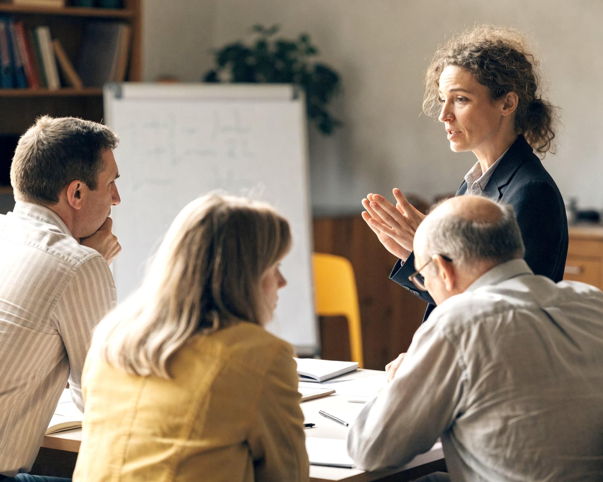 Trainerin leitet einen Workshop mit drei Teilnehmenden am Tisch
