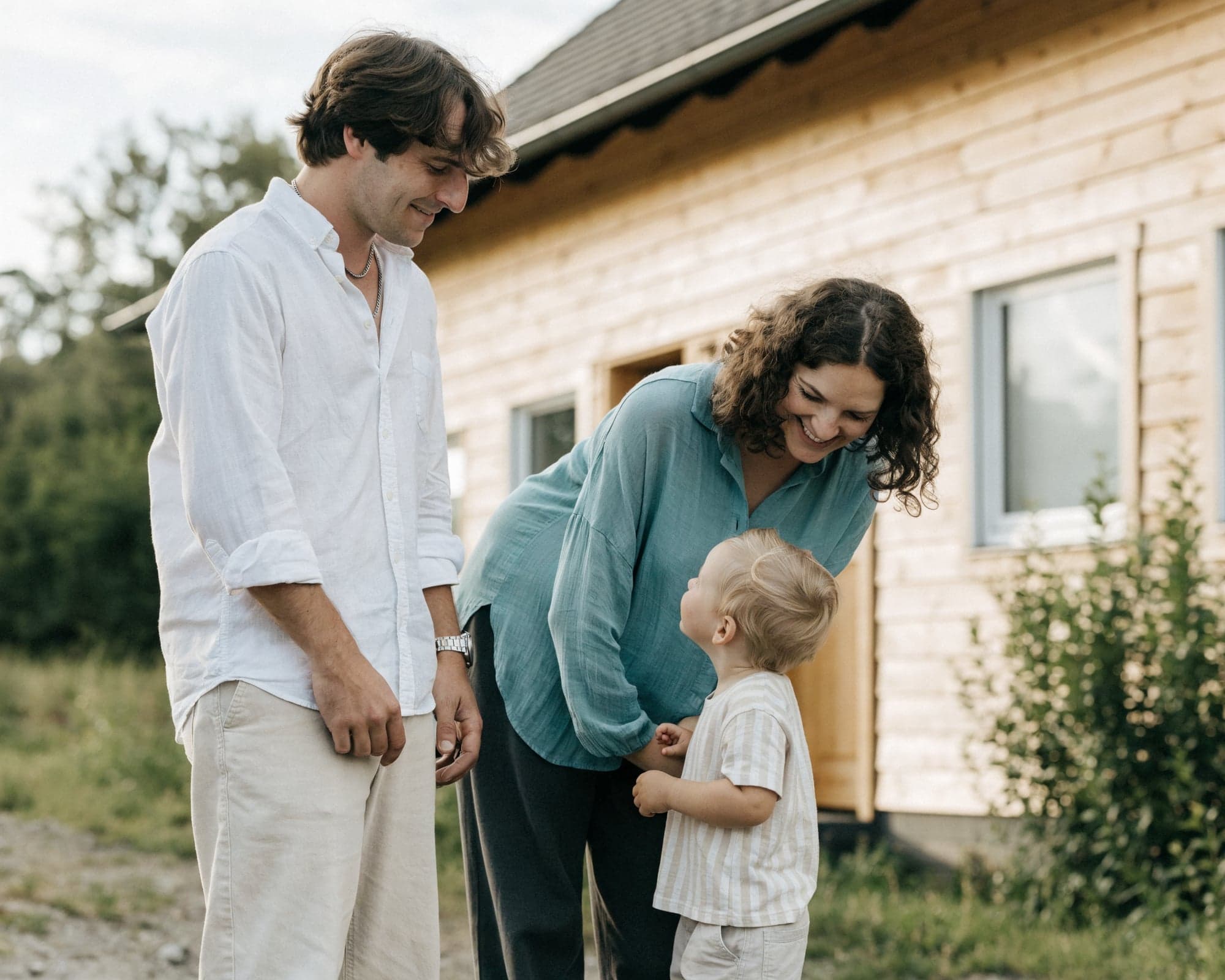 Junge Familie mit Kleinkind vor ihrem neu gebauten Haus
