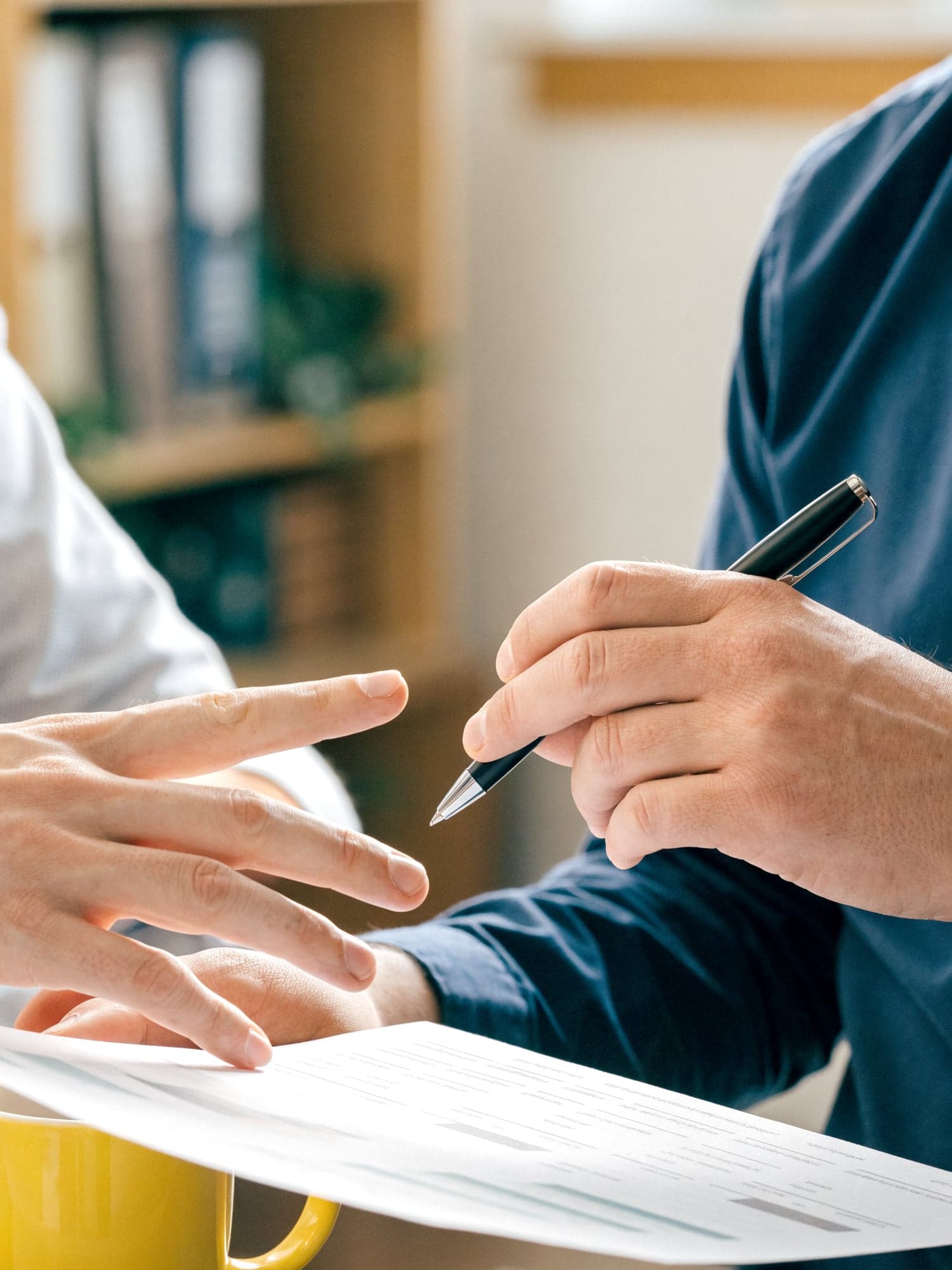 Hände zeigen mit einem Stift auf einen ausgedruckten Finanzplan
