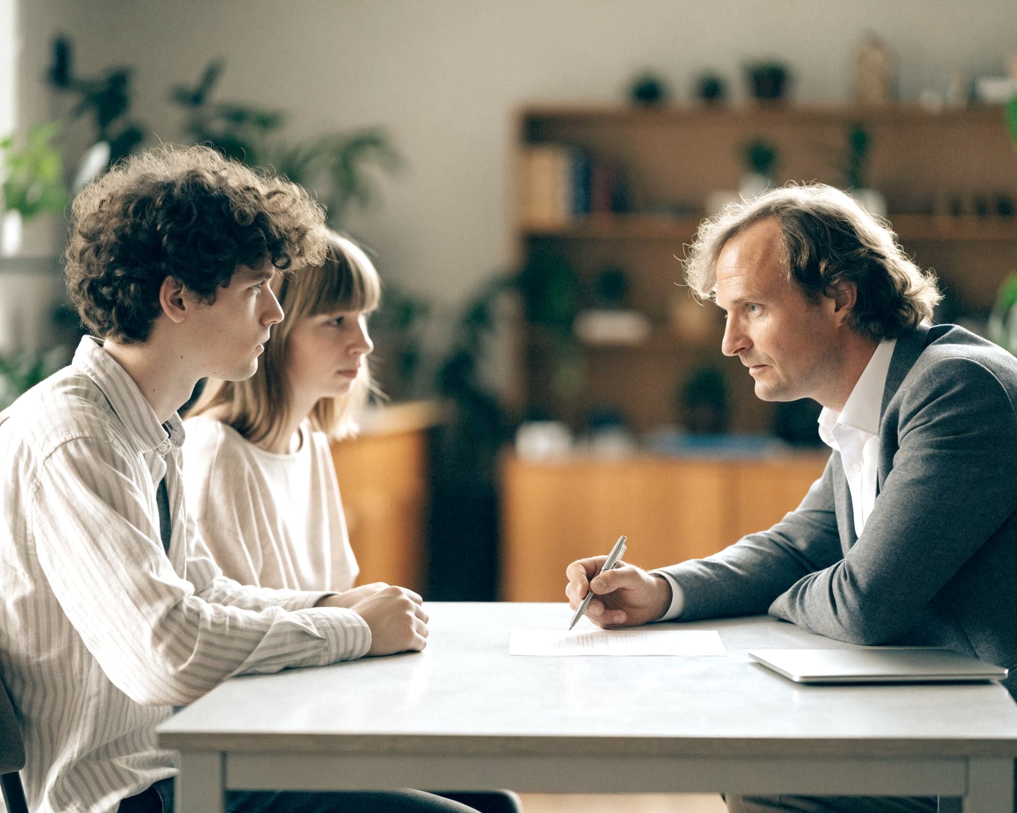 Finanzberater erklärt einem jungen Paar ein Dokument am Tisch