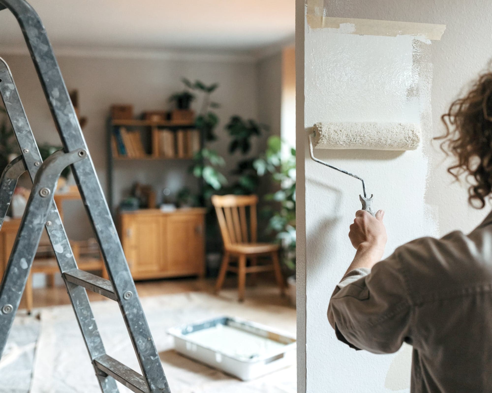 Maler rollt in einem Wohnzimmer frische Farbe an die Wand
