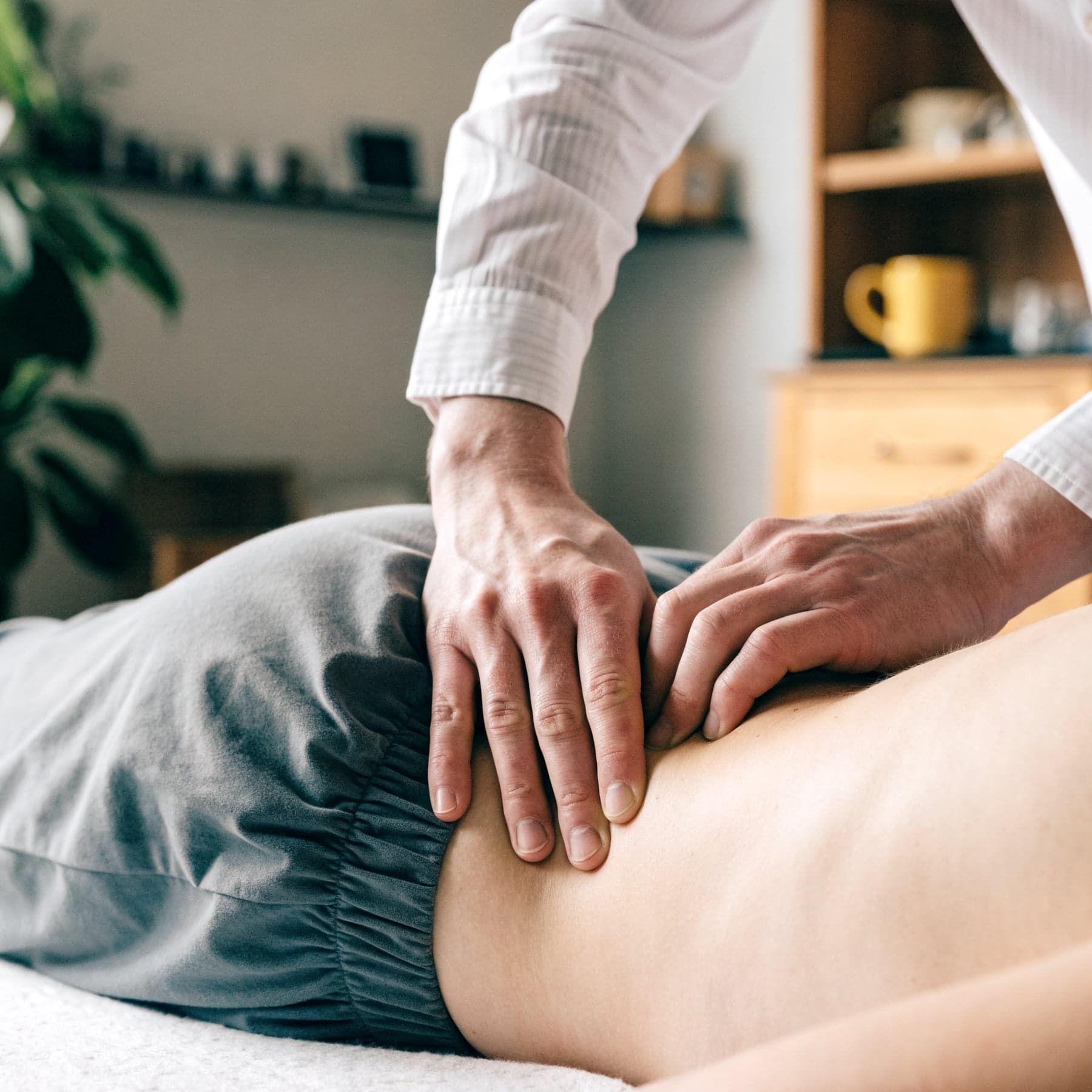 Manuelle Therapie: Hände der Therapeutin am Rücken eines Patienten
