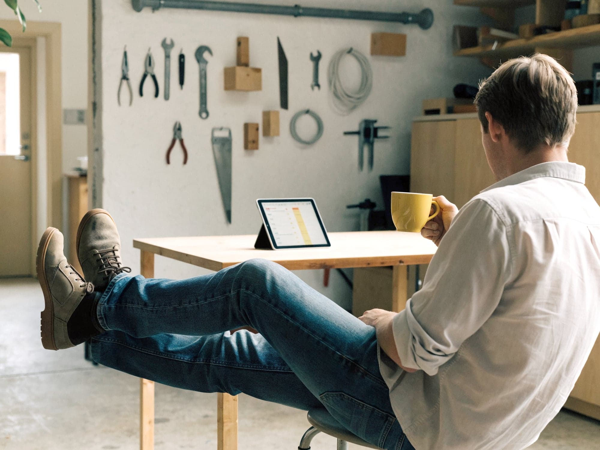 Handwerker lehnt sich zum Feierabend zurück, auf dem Tablet die Termine von morgen